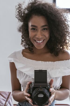 Good-looking young woman smiling with a big professional camera in her hands