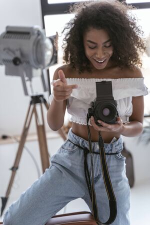 Smiling young woman turning on her big camera before shootingの写真素材