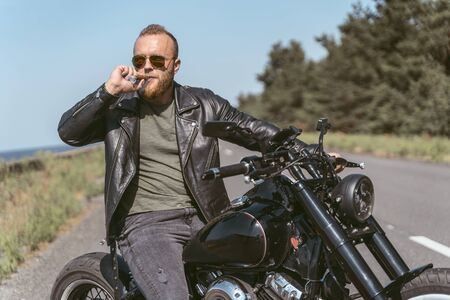 Attarctive bearded man with sigar posing on his motorcycle
