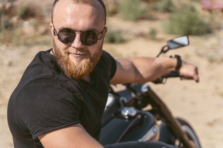 Portrait of an attractive athletic biker posing on his motorcycle