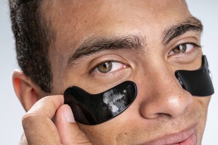 Close up picture of a young man taking off his black eye patches