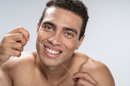 Good-looking young male being happy flossing his teethの写真素材