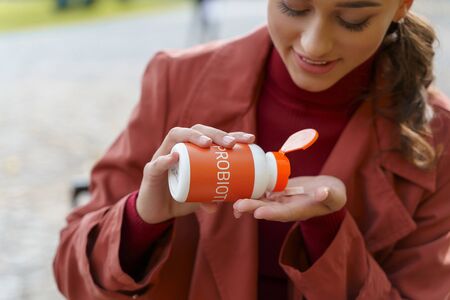 Good-looking young lady pouring probiotics out of the jarの写真素材