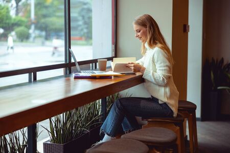 Side view of a cheerful young woman leaning over her exercise book