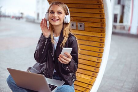 Lovely attractive young Caucasian student girl adjusting her headphonesの写真素材