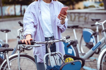 Cropped photo of a young woman standing with a bikeの写真素材