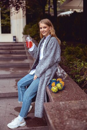 Smiling young lady with fruit juice looking at the camera