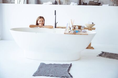 Pleased girl leaning on bath while waiting for proceduresの写真素材