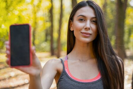 Pretty young woman raising her hand with a smartphone in it