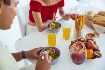 Friendly atmosphere. Cheerful young people being at home while enjoying their mealの写真素材