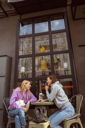 Favorite place. Cheerful longhaired female looking at her friend while having pleasant conversation