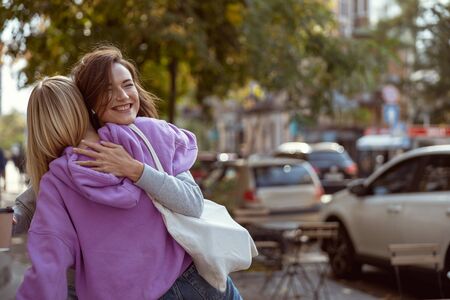 Warm atmosphere. Joyful female walking around the city, meeting her best friendの写真素材