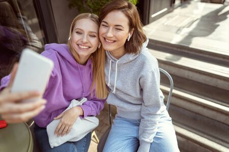 Cheerful brunette female expressing positivity while being in cafe with her friend