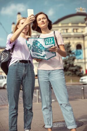 Look here. Attentive brunette girl holding city map and choosing the route of their walkの写真素材