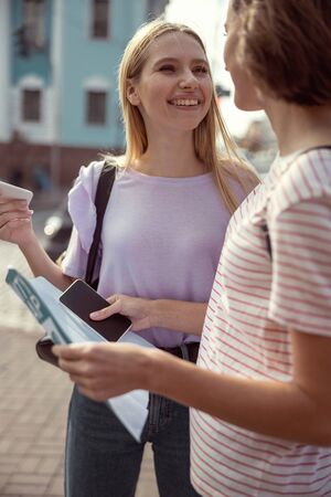 Positive delighted woman looking at her friend and talking about future tripの写真素材