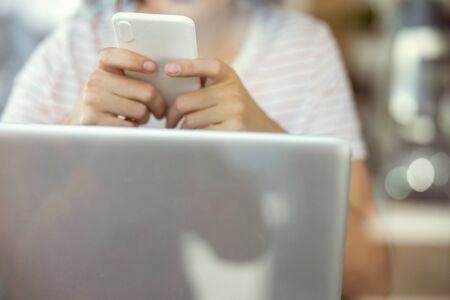 Lets chat. Concentrated woman leaning elbows on table while using telephone for chattingの写真素材