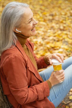 Happy woman with a citrus drink laughing in the parkの写真素材