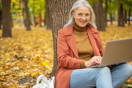 Happy modern lady with her laptop sitting on the groundの写真素材