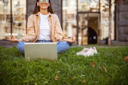Beautiful young woman sitting with her legs crossed in front of her laptopの写真素材