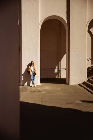 Good-looking young woman leaning on the wall in the sun