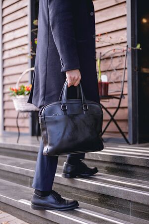Ready to go. Close up of male hand that carrying bag, young man standing on stairsの写真素材