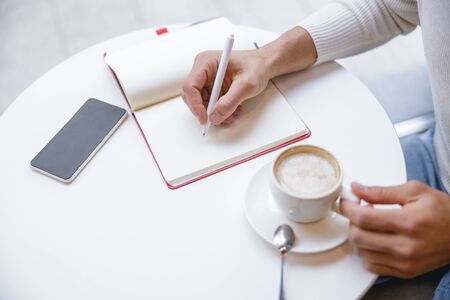 Time to relax. Relaxed male person going to drink coffee and fixing his ideas into his diaryの写真素材