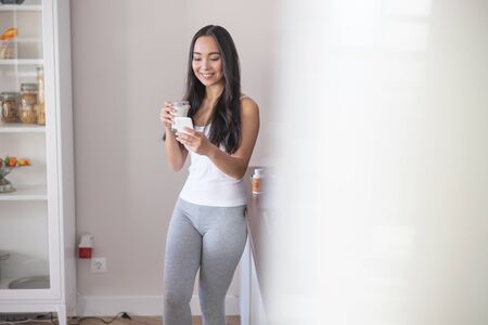 Good-looking smiling Asian woman standing near the countertopの写真素材