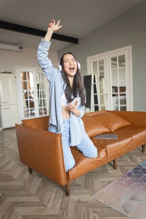 Cheerful lady in earphones having fun on the sofaの写真素材