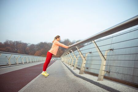 Beautiful lady in sportswear having morning work-out outdoors stock photo