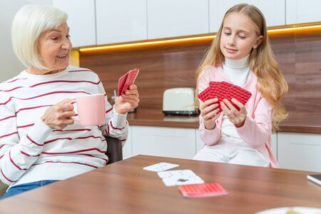 Senior woman and a girl looking at their playing cardsの写真素材