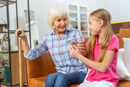 Caring young girl giving her grandmother a glass of water