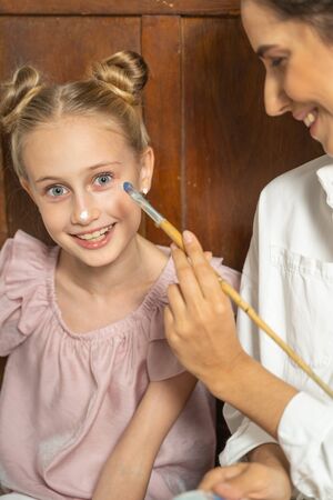 Cute young happy kid spending time with her mum and playing with paintbrush. Art concept