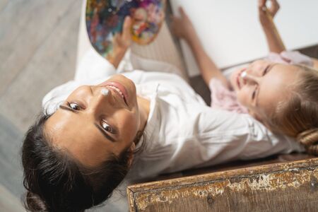 Happy Caucasian mum is ready for painting with her kid in art room. Art conceptの写真素材