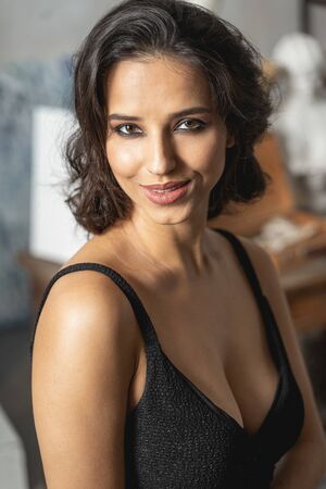 Elegant sexy lady in dark dress looking at camera during photosession. Female beauty concept
