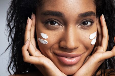 Smiling lady with cream on face posing for camera. Beauty concept