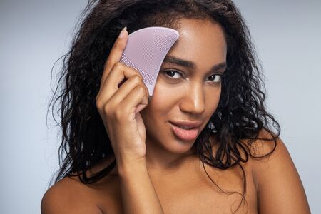Gorgeous young woman taking care of her facial skin against light background. Beauty and youth...