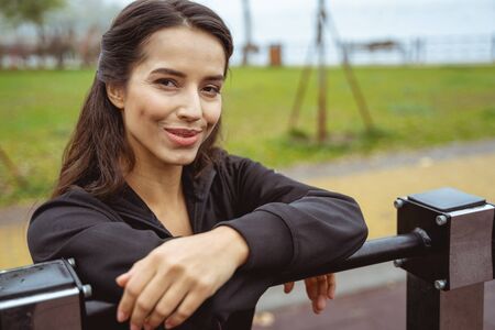 Natural beauty. Delighted young female posing on camera, leaning on chin-up barの写真素材
