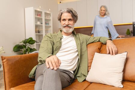 Dreamy man with legs crossed sitting alone on the couch