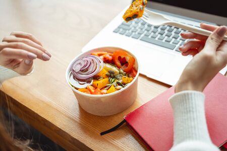 Bright colors. Relaxed girl sitting at the table in cafe while having lunch during workの写真素材