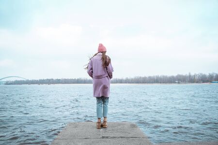 Young woman standing on the border and being deep in thoughtsの写真素材