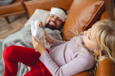 Adorable child holding toy cosmonaut while her dad lying on couch stock photoの写真素材