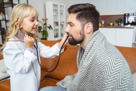 Adorable kid pretending to be nurse and examining her smiling dad stock photoの写真素材
