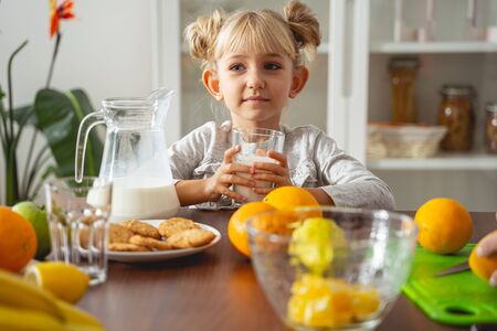 Cute child holding glass of milk and looking away stock photoの写真素材