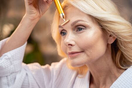 Close-up portrait of a female massaging her foreheadの写真素材