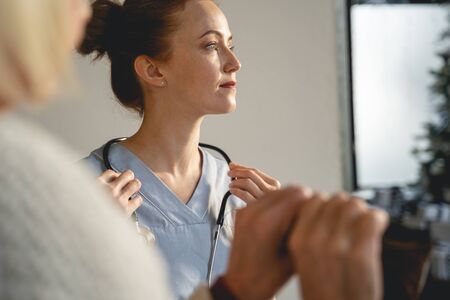 Kind medical worker looking forward while taking decision about treatmentの写真素材