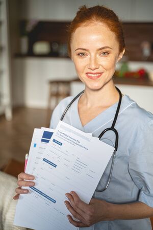 Cheerful female person wearing medical uniform while visiting her patient