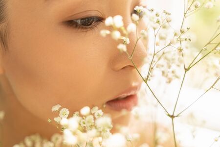 Asian tender woman smelling flowers. Female beauty conceptの写真素材