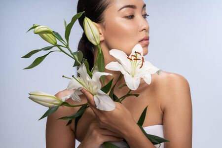 Asian serious woman holding flowers in hands. Female beauty conceptの写真素材