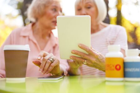 Close up picture of a cafe table with two old ladies sitting there and looking at the tabletの写真素材