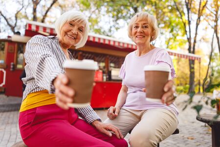 Cheerful old women sitting in front of a small coffee shop in the parkの写真素材